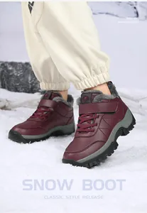 Bottes de neige bordeaux avec doublure en peluche grise sur fond de neige blanche
