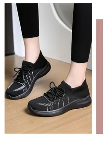 Dettaglio di sneaker in maglia nera con motivi bianchi e suola spessa ammortizzata