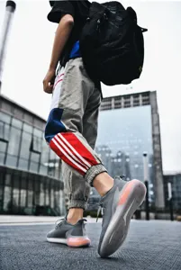 Detailed shot of breathable grey mesh sneakers with orange air cushion and street style jogger pants