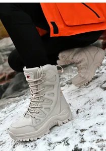 Close-up of beige tactical boots with non-slip rubber soles on snowy rocks