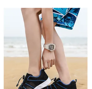 Nahaufnahme schwarzer atmungsaktiver Mesh-Schuhe mit blauen Akzenten am Sandstrand