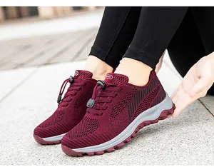 On-foot view of burgundy breathable mesh sneakers with quick-lace system on stone pavement