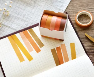 Detail of 5 rolls of 10mm earth tone washi tape in Autumn Leaves set on grid paper