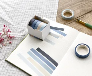 Detail of 5-roll blue washi tape set on a plaid notebook with lifestyle accessories