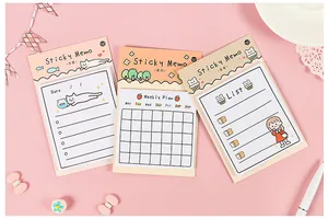 Detailed view of weekly planners and cat-themed sticky memos on a pink desktop