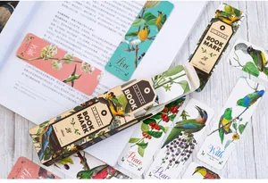Close-up of vintage bird illustration bookmarks on open book and wooden table
