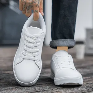 Minimalist white leather men sneakers with round toe and flat sole in outdoor setting