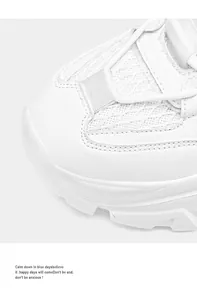 Detail of white chunky sneakers showing synthetic leather and mesh stitching with clean seams