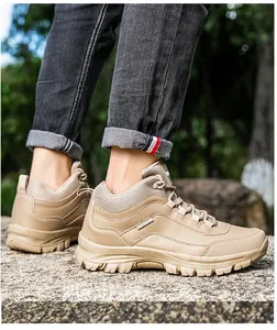 Close-up of durable khaki hiking boots with rugged rubber soles on outdoor rocky terrain