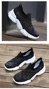 Detailed view of black knit slip-on sneakers with reflective sparkle and white geometric soles