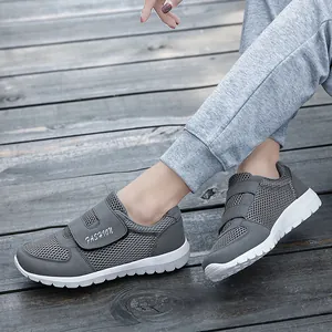 Graue atmungsaktive Mesh-Walkingschuhe mit Klettverschluss und modischem Text auf weißer Sohle