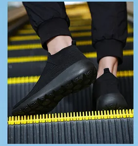 Close-up of black breathable knit sneakers showing the anti-slip rubber sole on an escalator