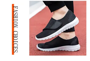 Side view of black mesh casual shoes with velcro strap on a red and white track