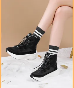 Detail of black winter boots with thick white soles and warm faux fur lining on a snow rug