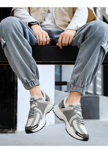 Dettaglio di sneakers retrò grigie con mesh traspirante su modello con pantaloni blu