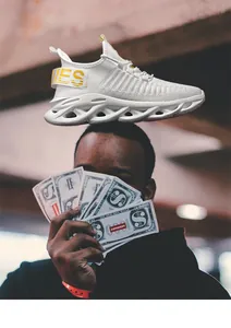Close-up of white knit sneakers with yellow heel strap and wavy hollowed-out shock sole