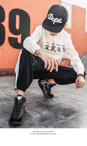 Streetwear style shot showing black and blue thick sole men sneakers with white hoodie