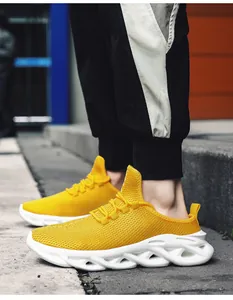 Λεπτομέρεια από κίτρινα mesh sneakers με λευκές κυματιστές σόλες φορεμένα στα πόδια