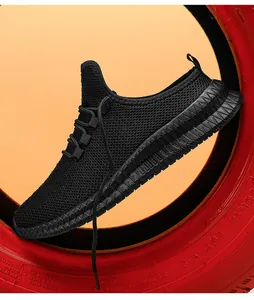 Nahaufnahme schwarzer atmungsaktiver Mesh-Sneaker auf rotem Reifen mit Gummisohle