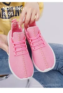Close-up of pink breathable mesh fabric and durable white thick sole on women's sports shoes