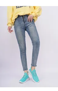 Detail of mint green mesh sneakers with white chunky soles and frayed light blue jeans