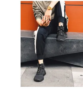 Detailed view of black high-top techwear sneakers with cross-straps on outdoor steps