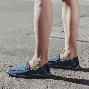 Men's dark blue denim slip-on loafers with fashion tag on a sunny outdoor street