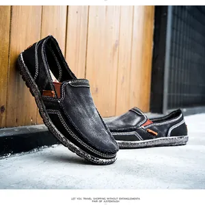 Detail view of black canvas slip-on shoes with white stitching and textured thick soles