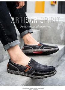 Detail of men's black canvas slip-on loafers with brown leather accents and white stitching