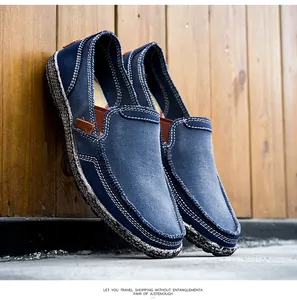 Detail of blue canvas slip-on shoe with white stitching and brown leather accent