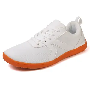 Minimalist low-top trainers with white mesh upper and vibrant orange rubber sole