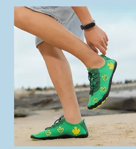 Detail of green quick-dry water shoes with yellow maple pattern on the beach sand