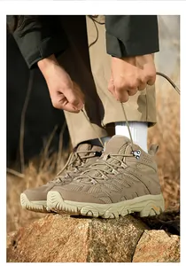 Close-up of durable khaki hiking boots with rugged soles and metal lace hooks