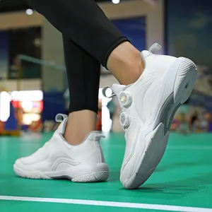 Weiße Hallensportschuhe mit doppeltem Drehverschluss auf grünem Spielfeld