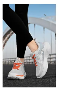 Makroaufnahme grauer Mesh-Sneaker mit orangefarbenen Akzenten und rutschfester Plateausohle