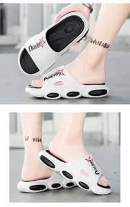 Detail of white beach slides with 'AREYOU FASHION' lettering and thick anti-slip sole