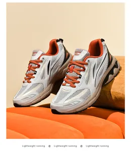 Detailed side view of breathable mesh sneakers with white, grey and orange color block design
