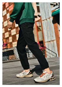 Outdoor street view of casual black jogger pants with elastic cuffs and side zipper detail