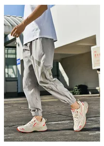Close-up of light gray casual joggers with large letter print and cuffed ankles on a model