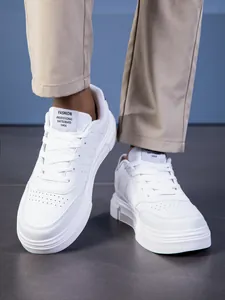 Primer plano de zapatillas de cuero blanco con perforaciones y etiqueta negra frontal