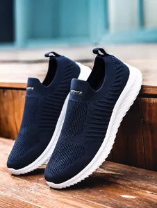 Detail of dark blue breathable knit slip-on sneakers on a rustic wooden staircase