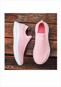 Detail view of pink breathable knitted slip-on sneakers on a rustic wooden background