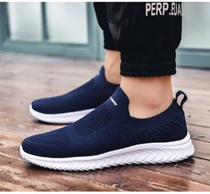 Detail shot of navy blue breathable knit slip-on sneakers with white soles on wood