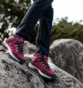 Detailaufnahme der rose-roten Outdoor-Wanderschuhe mit rutschfesten Sohlen auf felsigem Berggelände