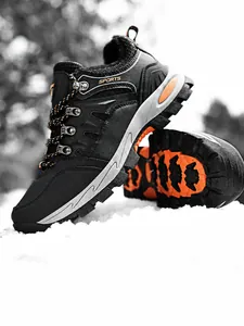 Detalle de botas de montaña negras y naranjas sobre fondo de nieve en exteriores