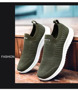 Detail of army green breathable knit slip-on sneakers with sports text on wooden stairs