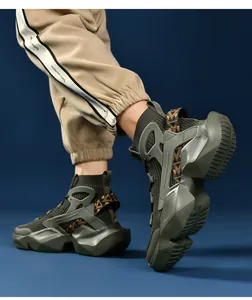 On-foot view of olive green high-top sock sneakers with thick soles and orange straps