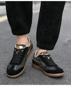 On-foot shot of black suede sneakers with gold detailing and classic gum soles