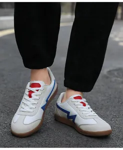 Outdoor shot of classic white leather retro trainers with gum soles and blue accents