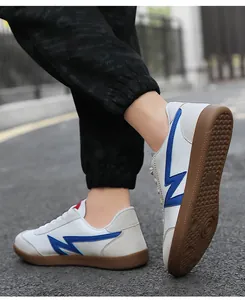 Close-up of retro sneakers with blue logo, grey suede patches and brown gum sole
